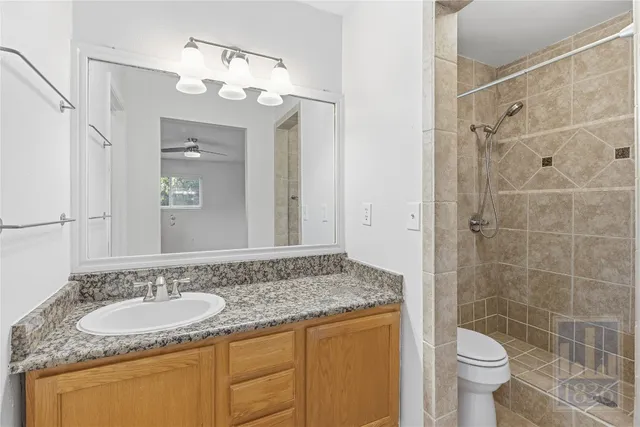 a bathroom with a granite countertop sink a toilet a mirror and shower