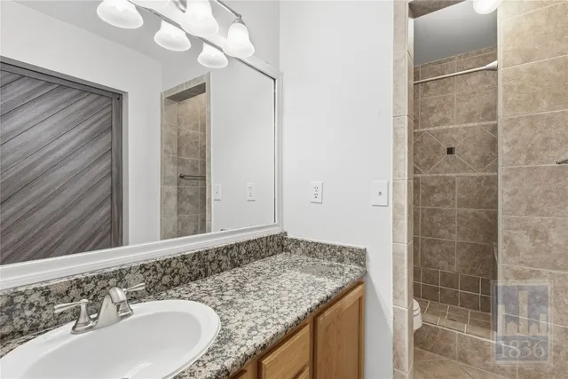 a bathroom with a granite countertop sink a toilet and a mirror