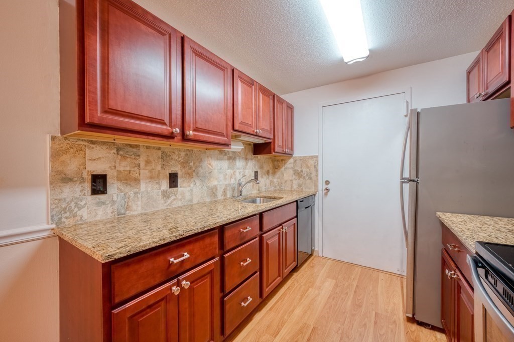 3 Post Oak Lane, Unit 4 Natick, MA 01760 - Photo 11 of 34 a kitchen with stainless steel appliances granite countertop a refrigerator a sink dishwasher and wooden cabinets with wooden floor