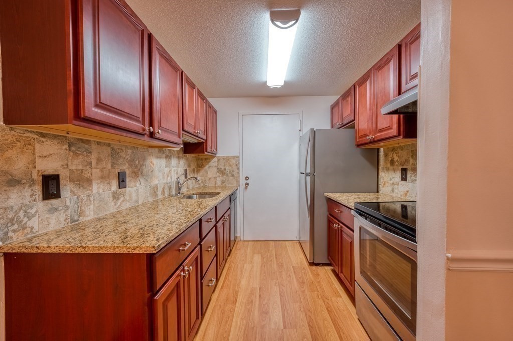 3 Post Oak Lane, Unit 4 Natick, MA 01760 - Photo 12 of 34 a kitchen with granite countertop a sink stove and refrigerator