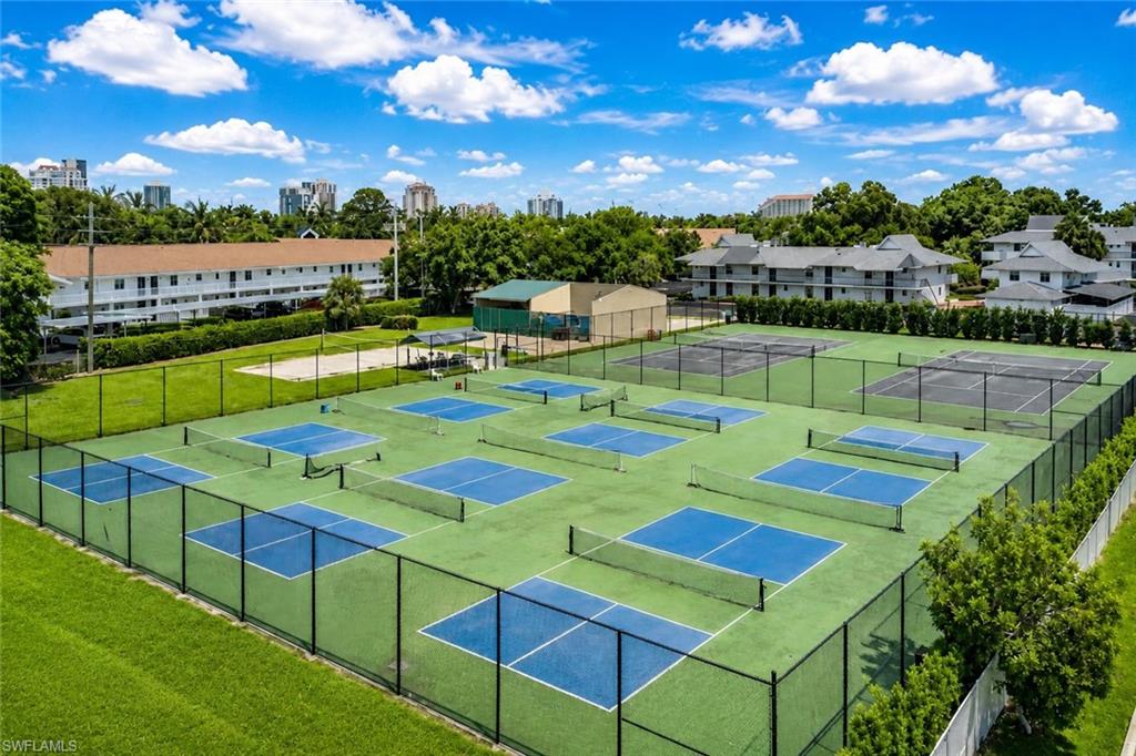 600 Neapolitan Way, Unit 449 Naples, FL 34103 - Photo 5 of 44 Multiple fenced pickleball courts with blue playing surfaces and green surrounds
