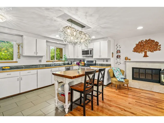 a kitchen with stainless steel appliances granite countertop a table chairs and a refrigerator
