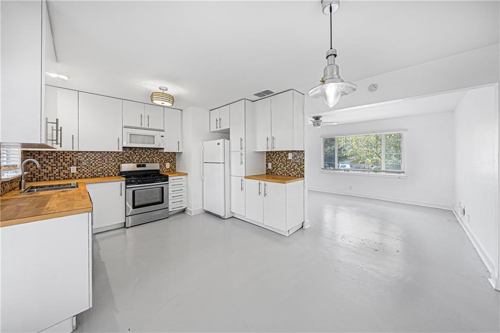 a kitchen with stainless steel appliances kitchen island granite countertop a refrigerator a stove oven and white cabinets with wooden floor