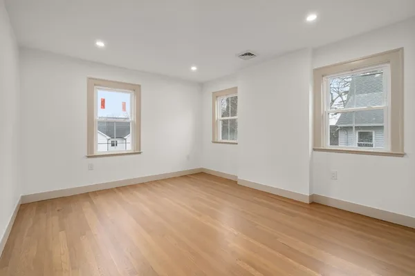 a view of an empty room with a window and wooden floor