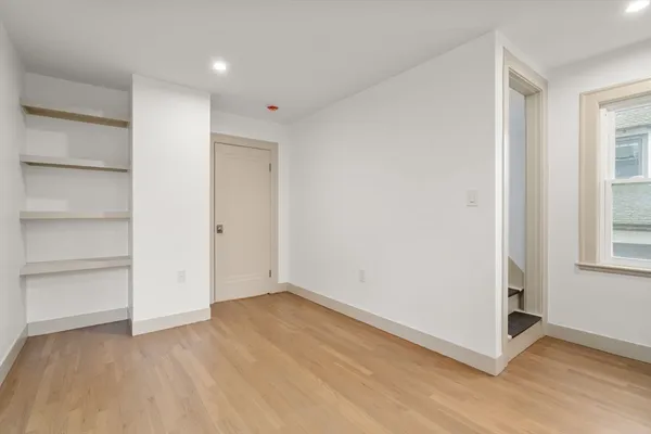 a view of an empty room with a window and wooden floor