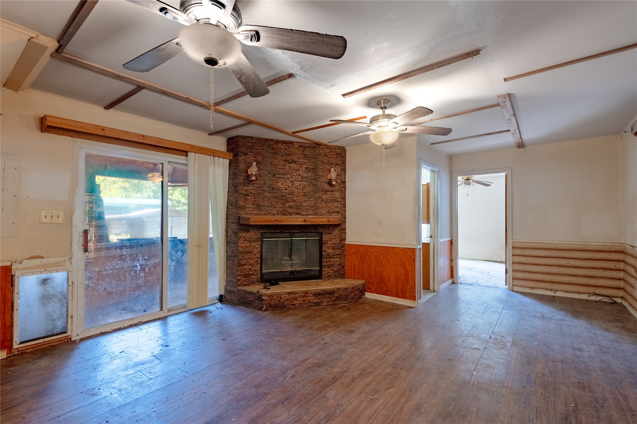 8 Creek Road Huntsville, TX 77320 - Photo 11 of 50 Spacious living area featuring a rustic stone fireplace, ceiling fans, and sliding glass doors that offer ample natural light.