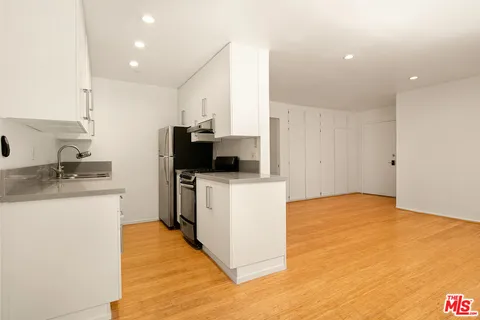 a kitchen with a sink and a stove top oven with wooden floor