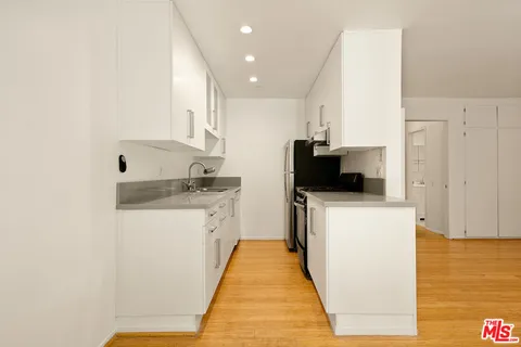 a kitchen with stainless steel appliances a refrigerator sink and white cabinets