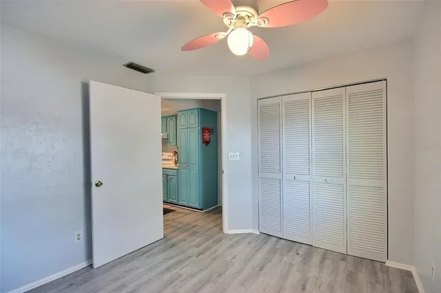 an empty room with wooden floor closet and windows