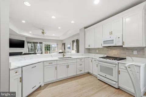 a open white kitchen with center island and stainless steel appliances
