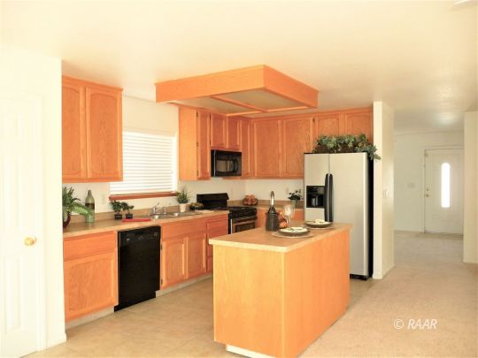 1129 Porter Street Ridgecrest, CA 93555 - Photo 5 of 22 a kitchen with refrigerator a stove a sink and a microwave