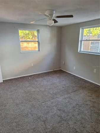 an empty room with windows and ceiling fan