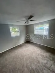 an empty room with windows and fan
