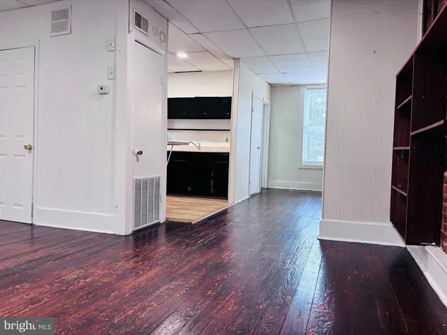 a view of an empty room with wooden floor and a fireplace