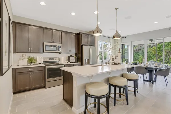 a kitchen with kitchen island granite countertop a table chairs stove and refrigerator