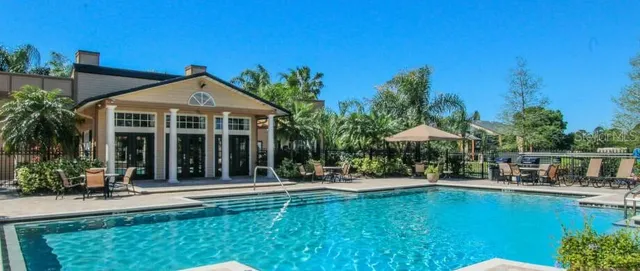 a patio with a table and chairs under an umbrella with palm trees