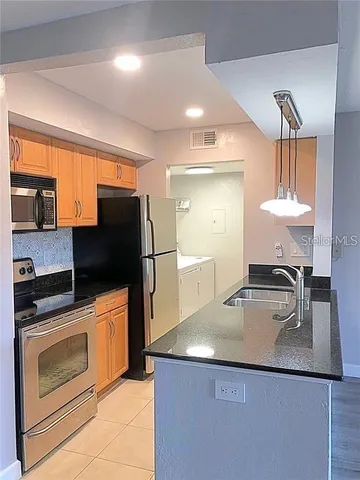 a kitchen with stainless steel appliances granite countertop a sink and a refrigerator