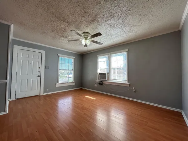 a view of an empty room with wooden floor and a window
