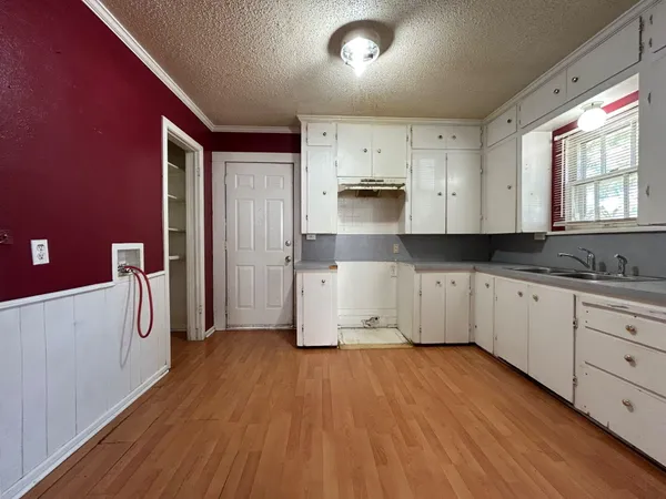 a kitchen with wooden floors and white cabinets