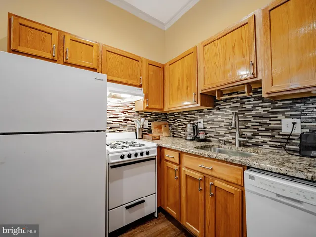 a kitchen with stainless steel appliances granite countertop a sink a stove a refrigerator a washer and dryer