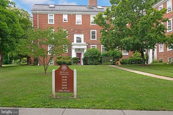 a view of a brick house with a yard and large trees