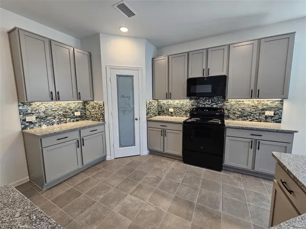 a kitchen with stainless steel appliances granite countertop a stove top oven a sink and dishwasher a refrigerator with white cabinets