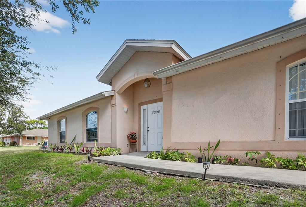 Doorway to property featuring stucco siding and a lawn