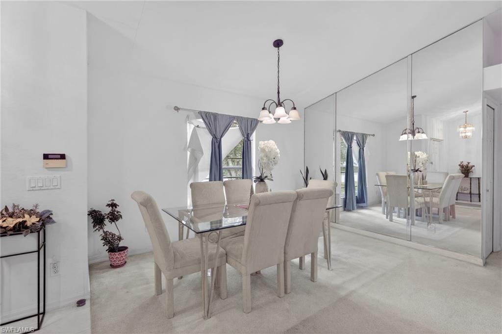 3920 10th Street North Naples, FL 34103 - Photo 16 of 47 Dining area featuring light colored carpet and a chandelier