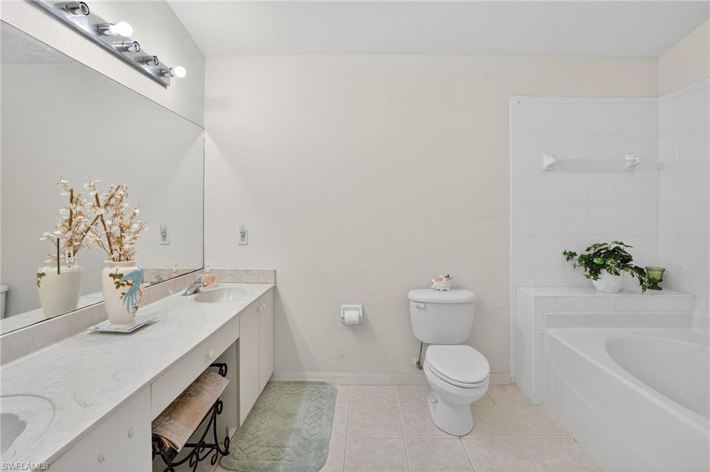 3920 10th Street North Naples, FL 34103 - Photo 35 of 47 Bathroom with double vanity, a tub, and light tile patterned floors