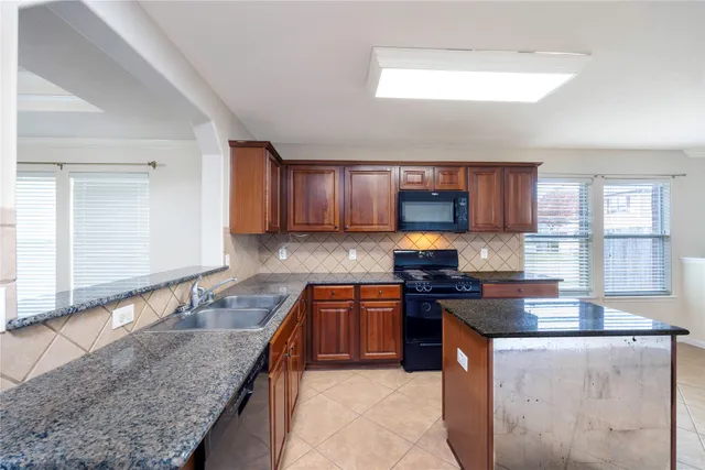 a kitchen with stainless steel appliances granite countertop a stove a sink and a microwave