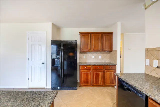 a view of kitchen with granite countertop cabinets and refrigerator