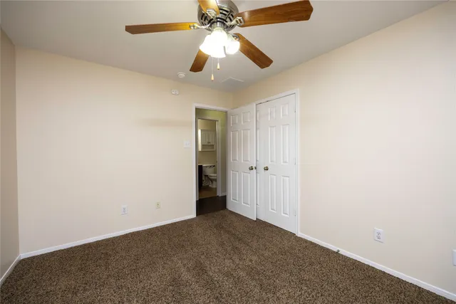 an empty room with a chandelier fan and closet