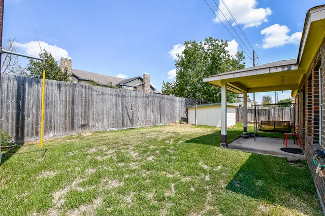 a view of a backyard with table and chairs under an umbrella with wooden fence