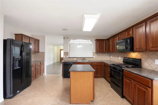 a kitchen with stainless steel appliances granite countertop a stove a sink dishwasher a refrigerator and a microwave oven