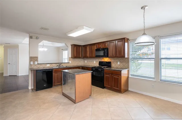 a kitchen with stainless steel appliances granite countertop a stove top oven a sink dishwasher a refrigerator and a fireplace