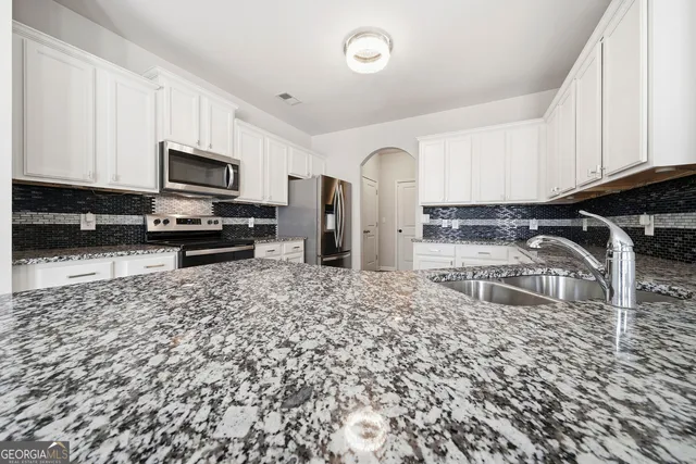 a kitchen with granite countertop a stove a sink and a microwave