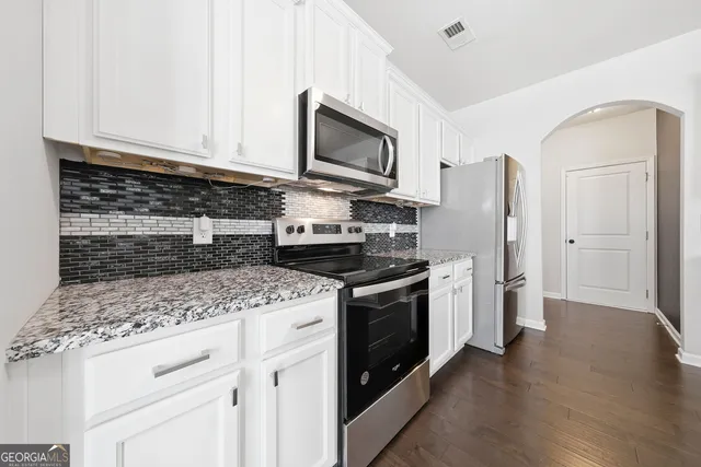 a kitchen with stainless steel appliances granite countertop a stove a refrigerator and a microwave
