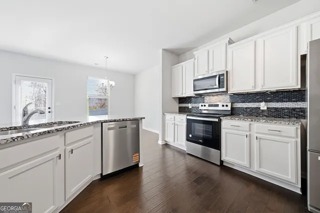 a kitchen with granite countertop white cabinets and stainless steel appliances