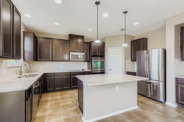 a kitchen with stainless steel appliances granite countertop a sink a stove a refrigerator and island