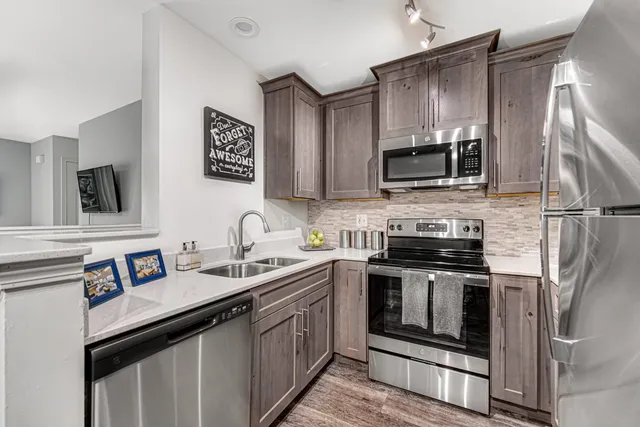 a kitchen with stainless steel appliances granite countertop a sink stove microwave and refrigerator