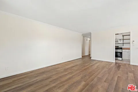 a view of an empty room with wooden floor and a ceiling fan