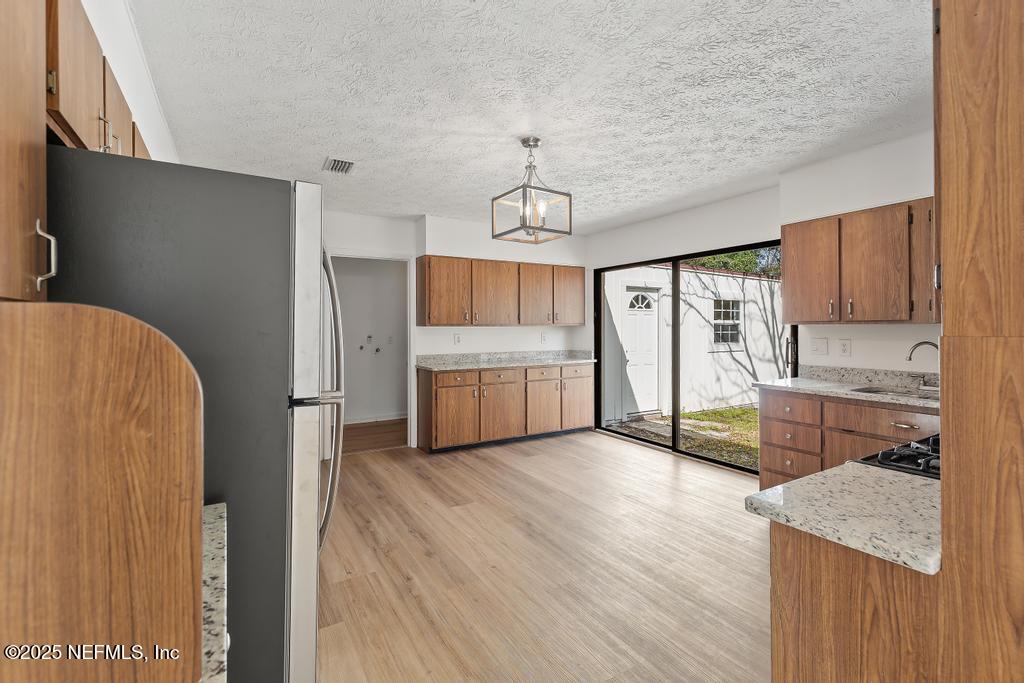 54074 Charles Street Callahan, FL 32011 - Photo 25 of 52 a kitchen with granite countertop a refrigerator a sink dishwasher a stove and white countertops with wooden floor