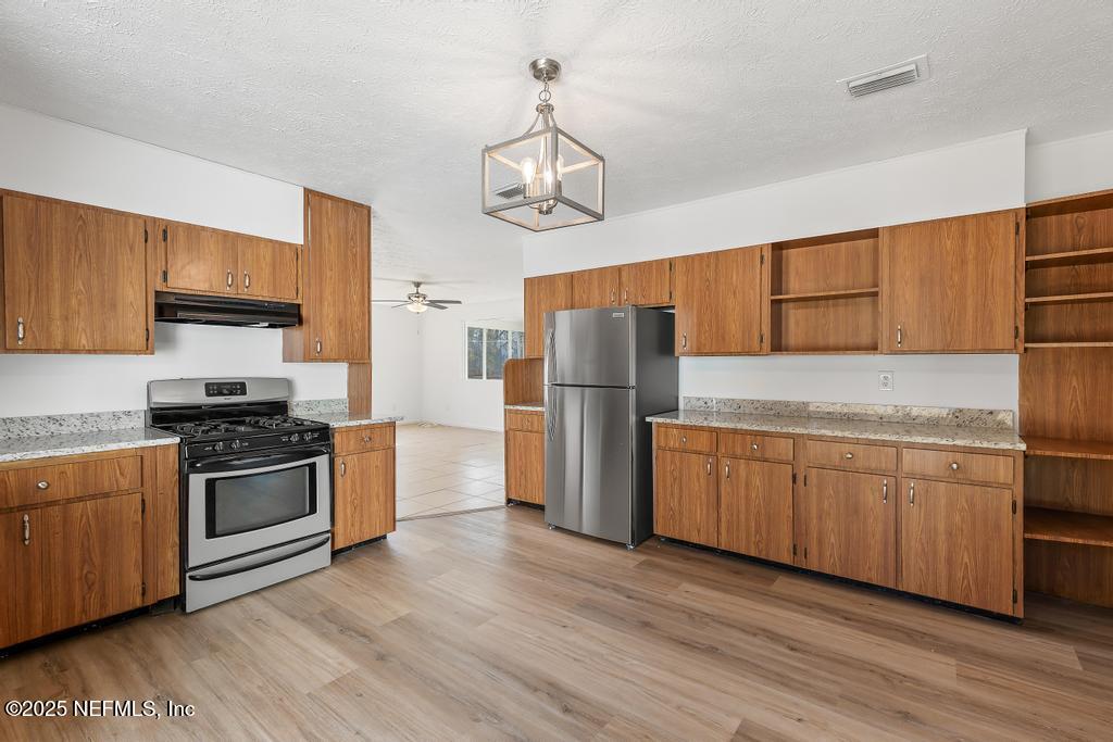 54074 Charles Street Callahan, FL 32011 - Photo 28 of 52 a kitchen with stainless steel appliances granite countertop a refrigerator a stove top oven a sink and dishwasher with wooden floor