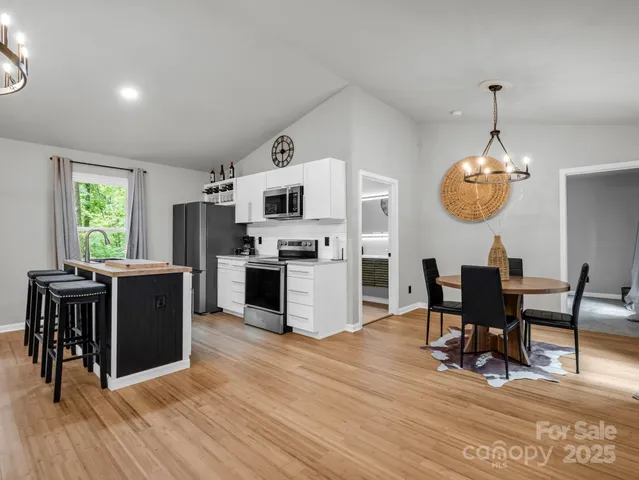 a kitchen with stainless steel appliances granite countertop a stove top oven a refrigerator a dining table and chairs with wooden floor