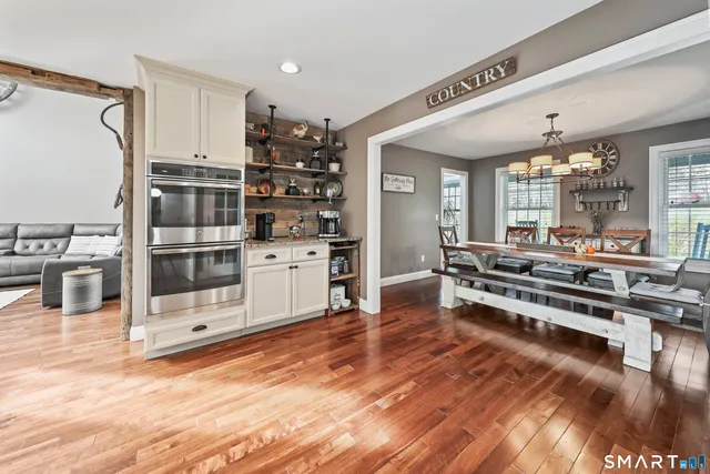 a large white kitchen with stainless steel appliances wooden floor and counter space