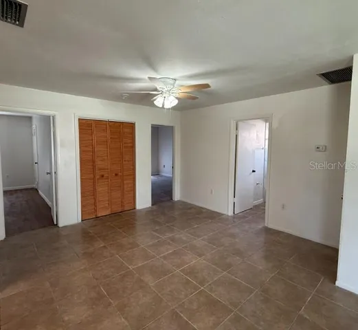 an empty room with closet and a ceiling fan