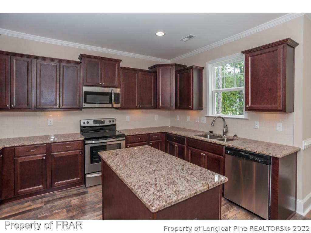 350 Kerr Lake Road Aberdeen, NC 28315 - Photo 15 of 34 a kitchen with a sink stove top oven and wooden cabinets