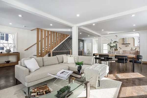 a living room with furniture kitchen view and a wooden floor