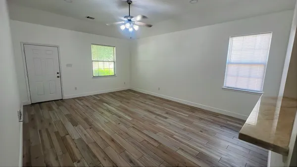 a view of empty room with wooden floor and fan
