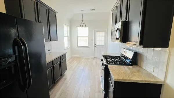 a kitchen with granite countertop a refrigerator stove and sink